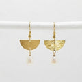 A pair of gold geometric dangle earrings with textured semi-circles and hanging pearl drops, displayed on a white horizontal bar against a light gray background.