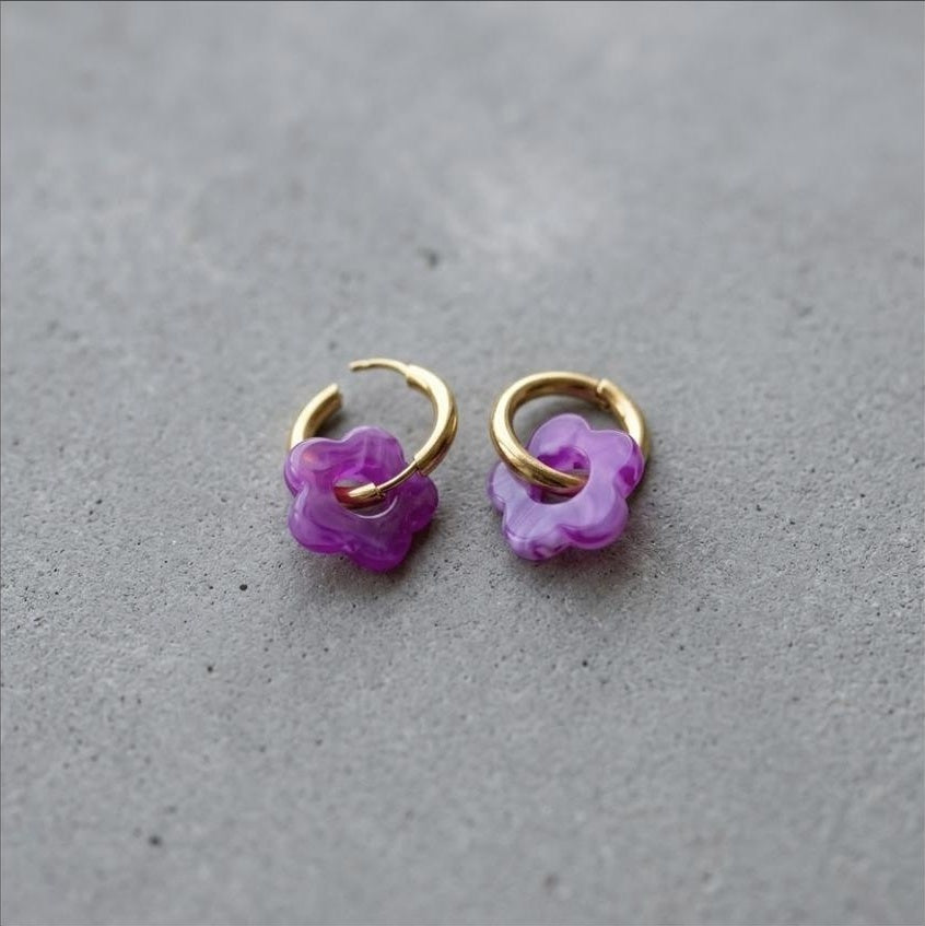 A pair of small hoop earrings with dangling translucent purple flower charms.